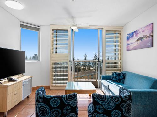 a living room with a blue couch and a tv at Mariner Shores Club in Gold Coast