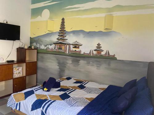 a bedroom with a bed with a painting on the wall at Jasmin Homestay in Sanur