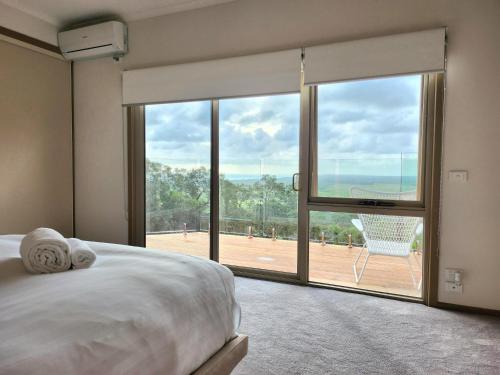1 dormitorio con 1 cama y una gran ventana de cristal en Cape Schanck Golf and Ocean Views Holiday Villa, en Cape Schanck