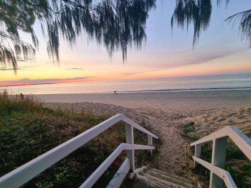 a staircase leading to the beach at sunset at Rosalynda- Luxury Beachfront 3 BR Townhouse in Hervey Bay