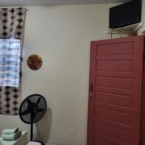 a room with a red door and a fan at Hacienda Tropical Guest House in Belmopan