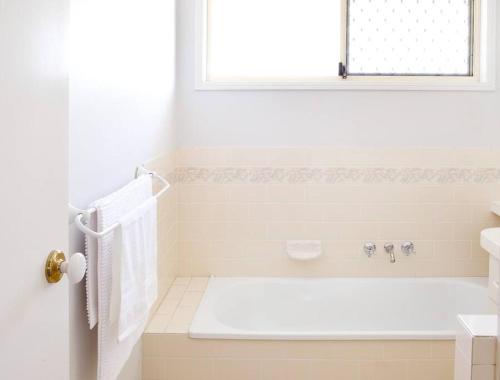 baño blanco con bañera y ventana en Spacious Two-Bedroom Retreat, en Ipswich