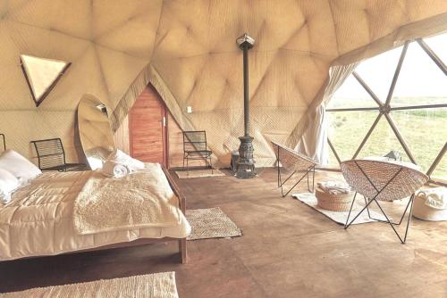 a bedroom with a bed and chairs in a tent at FARMGLAMP in Balneario Buenos Aires