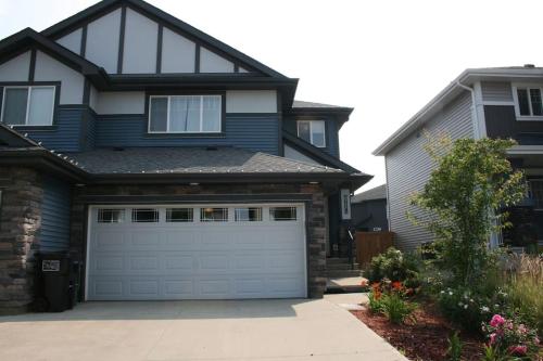 a house with a garage door in front of it at Entire Home AC 4Beds Sleeps 8 Double Garage Near WEM Free Wifi & Netflix in Edmonton