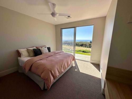 - une chambre avec un lit et une grande fenêtre dans l'établissement Middle River Vista Beach House, à Stokes Bay