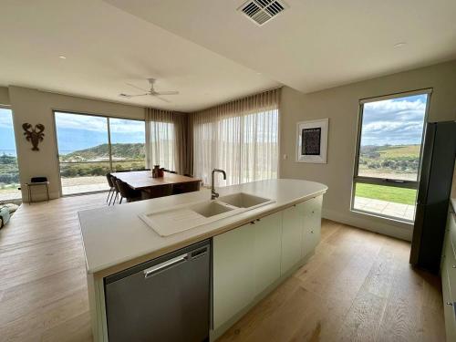 a kitchen with a sink and a table and windows at Middle River Vista Beach House in Stokes Bay