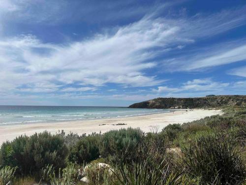 a beach with people walking on the sand and the ocean at Middle River Vista Beach House in Stokes Bay