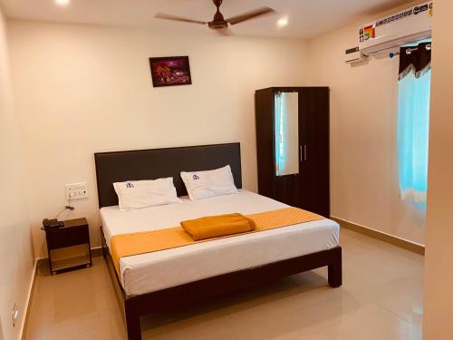 a bedroom with a bed with an orange blanket at Hotel Sitar Grand in Tirupati