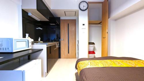 a kitchen with a microwave and a bed in a room at KIYAZA Station Sapporo 2 in Sapporo