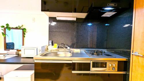 a kitchen with a sink and a microwave at KIYAZA Station Sapporo 2 in Sapporo