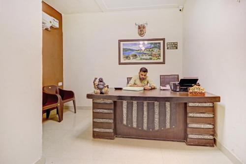 um homem sentado numa secretária num quarto em OYO Hotel Sky View em Ludhiana