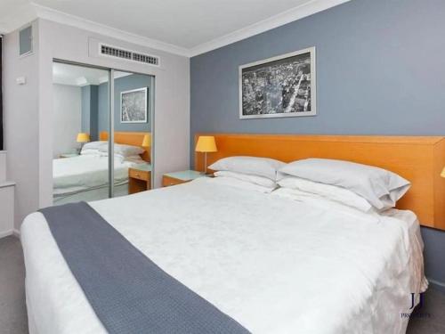 - une chambre avec un grand lit blanc et un miroir dans l'établissement CBD 1 Bed Apt with Riverview and Parking, à Brisbane