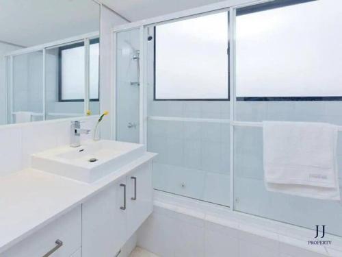 La salle de bains blanche est pourvue d'un lavabo et d'une douche. dans l'établissement CBD 1 Bed Apt with Riverview and Parking, à Brisbane