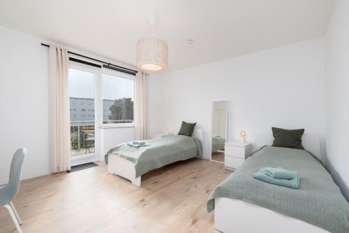 ein weißes Schlafzimmer mit 2 Betten und einem Fenster in der Unterkunft Chic Apartment with balcony in Wolfsburg