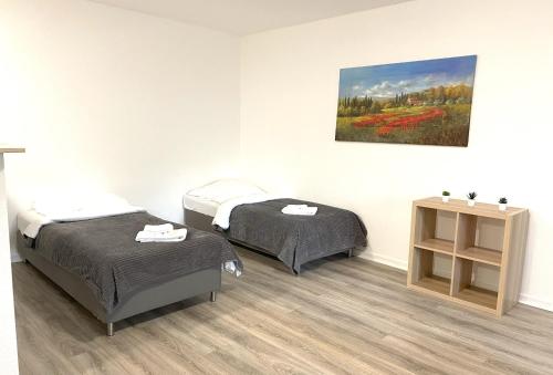 two beds in a room with a painting on the wall at City Apartments in Neuss
