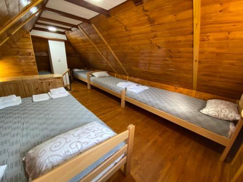 two beds in a room with wooden walls at Grande Apartman Nature Connection Drina in Bajina Bašta