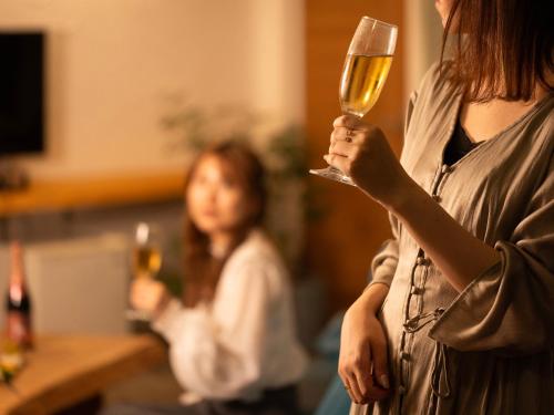 a woman holding a glass of wine in her hand at Hoshi No Terrace Motobu Yamazato in Motobu