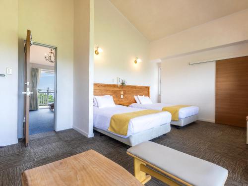 a hotel room with two beds and a balcony at Hoshi No Terrace Motobu Yamazato in Motobu