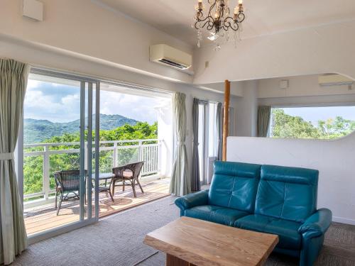 a living room with a blue couch and a balcony at Hoshi No Terrace Motobu Yamazato in Motobu