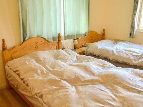 two unmade beds in a bedroom with a window at Tree Village Karuizawa in Karuizawa