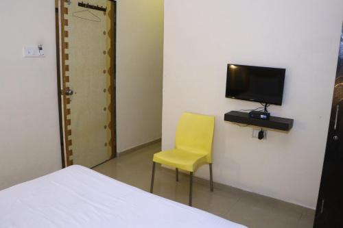 a yellow chair in a room with a television at Neuaura Stays in Mahabaleshwar