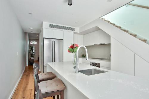 una cucina con armadi bianchi e piano di lavoro bianco di 3 Bedrooms - Darling Harbour - Junction St 2 E-Bikes Included a Sydney