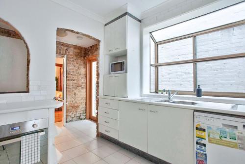 cocina blanca con fregadero y ventana en 3 Bedrooms - Darling Harbour - Darghan Street 2 E-Bikes Included en Sídney