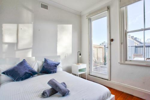 Un dormitorio con una cama con almohadas azules y una ventana en 3 Bedrooms - Darling Harbour - Darghan Street 2 E-Bikes Included en Sídney
