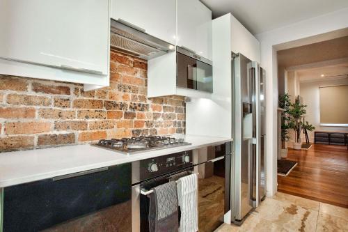 een keuken met witte werkbladen en een bakstenen muur bij 3 Bedrooms - Darling Harbour - Ada Place in Sydney