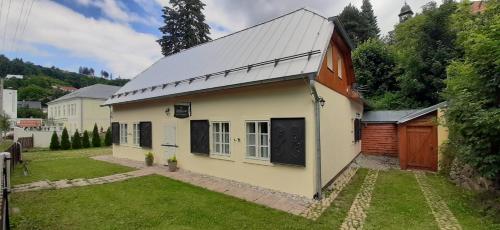 a small white house with a metal roof at Boutique Hotel Siglisberg in Štiavnické Bane