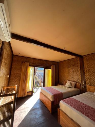 a bedroom with two beds and a window at Coral Voice 1 Homestay & Lumbung in Gili Trawangan