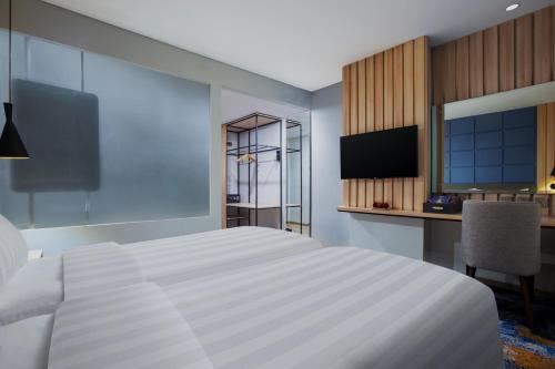 a bedroom with a large white bed and a desk at Aston Pekalongan Syariah Hotel & Conference Center in Pekalongan