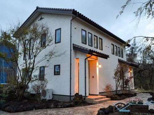 a white house with its lights on at Tree Village Karuizawa in Karuizawa