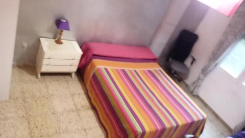 a small room with a bed and a night stand at piso completo. in San Vicente del Raspeig