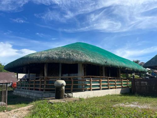 eine Hütte mit einem Strohdach darüber in der Unterkunft Maria Kulafu Kubo House Kinamaligan beside Eglin Gas Station 