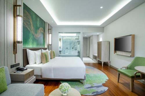 a bedroom with a white bed and a tv at Mason Pine Hotel Bandung in Padalarang