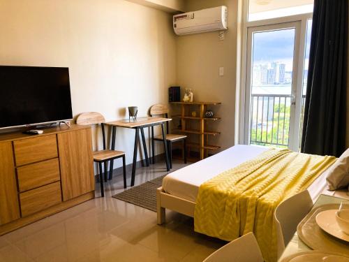a hotel room with a bed and a television and a table at BH Mangrove Condos in Mactan