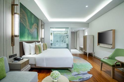 a bedroom with a white bed and a tv at Mason Pine Hotel Bandung in Padalarang