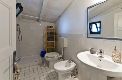 un bagno con lavandino, water e specchio di Rustico al mare a Capo Mulini