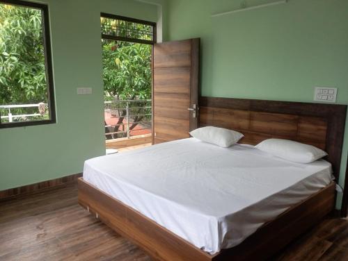 1 dormitorio con 1 cama con sábanas blancas y 2 ventanas en Crescent Moon Homestay, en Rishīkesh