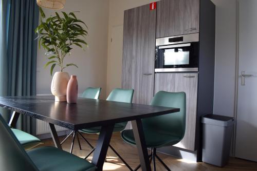 a dining room with a table and green chairs at Camping Duin en Strand in Scharendijke