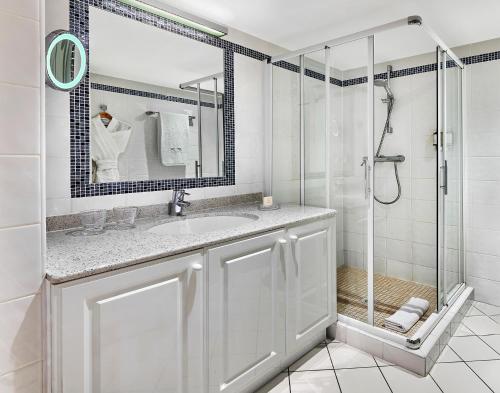 een witte badkamer met een douche en een wastafel bij La Résidence de La Réserve in Beaulieu-sur-Mer