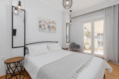 Un dormitorio blanco con una cama blanca y una ventana. en Stavroula's House City Center, Penthouse, en Tesalónica