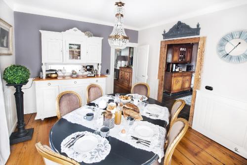 comedor con mesa, sillas y reloj en Le Clos Marguerite - Maison d'Hôtes, en Ammerschwihr