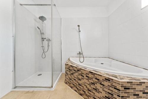 uma casa de banho com uma banheira e um chuveiro em vidro. em Chic & Modern Apartment em Jüterbog