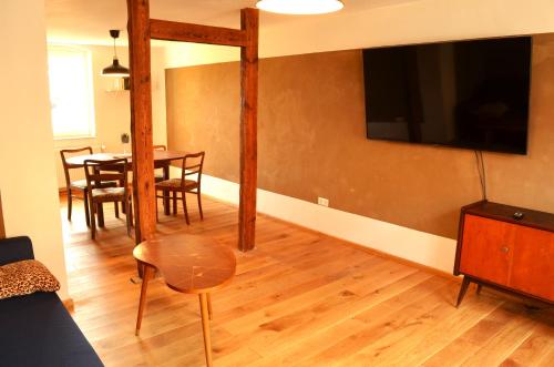 a living room with a table and a television on the wall at Lehmhäuschen mit Sauna in Tangermünde