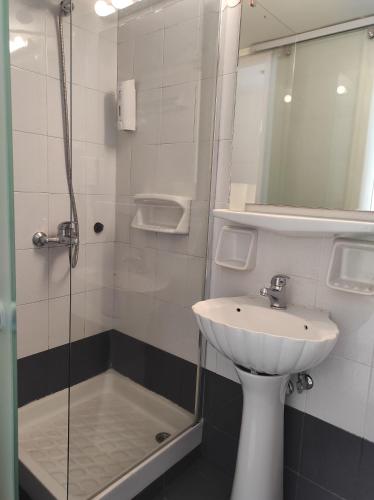 a bathroom with a sink and a glass shower at Filoxenia Beach Hotel in Rethymno Town