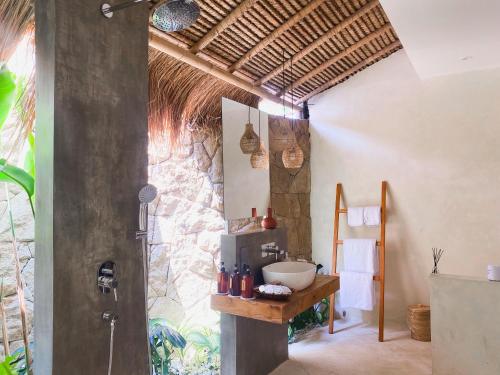 ein Bad mit einem Waschbecken und einer Dusche in einem Zimmer in der Unterkunft Reset Lombok Hotel in Kuta Lombok