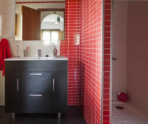 a bathroom with a sink and a red tile wall at El Rincón del Tiétar in Santa Maria del Tietar
