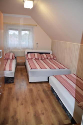 ハイドゥソボスローにあるHarsányi Vendégházのウッドフロアの小さな部屋のベッド2台